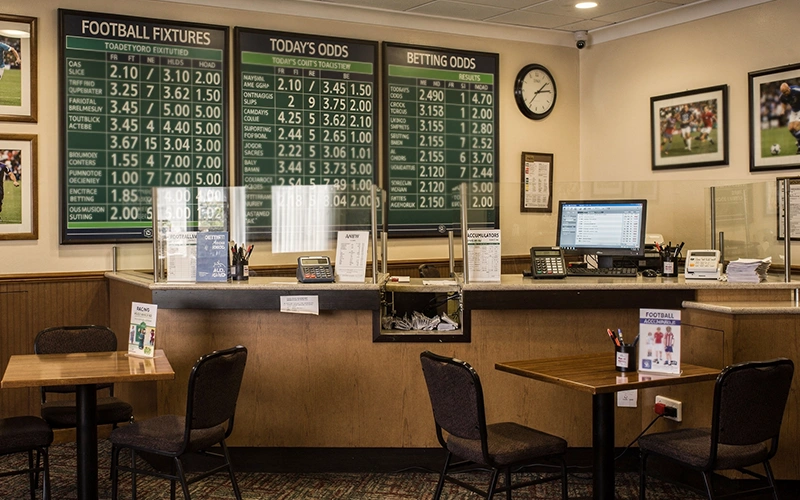 Buchmacher-B&uuml;ro mit Wettanzeigen im Hintergrund